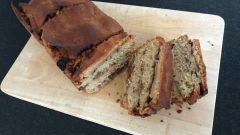 Ein frisch gebackenes Apfel-Zupfbrot liegt auf einem Holzbrett, einige Stücke sind bereits herausgetrennt.