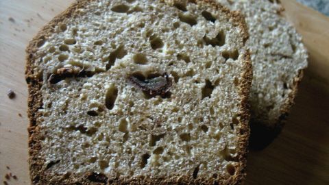 Sahnige Scheiben Bananenbrot liegen auf einem Holzbrett, umgeben von Krümeln und einem neutralen Hintergrund.