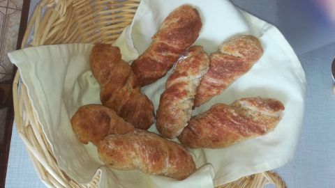 Ein Korb enthält mehrere frisch gebackene Topinambur-Brote, die appetitlich auf einem hellen Tuch angeordnet sind.