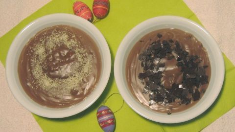 Zwei Schalen mit Schoko-Vanille-Pudding, der mit Kokosraspeln und Schokoladenstückchen garniert ist, auf einer grünen Serviette.