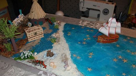 Eine Schatzinsel-Deko zeigt eine Miniatur mit einem Boot, Strand und blauer See, ideal für Geschenke und Feiern.