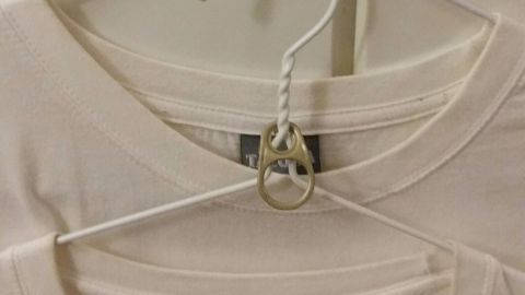 Ein weißes T-Shirt hängt an einem speziellen Haken im Kleiderschrank, optimal platziert zur Raumnutzung.