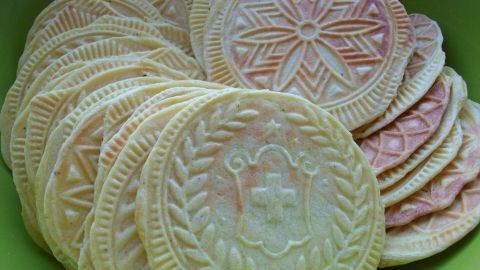 Käse-Kräuter-Brezeli liegen gestapelt in einer grünen Schüssel, dekoriert mit traditionellen Mustern und leicht gebräunt.
