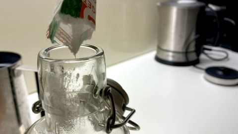 Eine transparente Glas-Trinkflasche wird mit Reinigungsmittel befüllt, um vergilbte Stellen zu beseitigen.