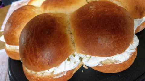 Die Semlor-Tarta präsentiert sich als weiche, runde Weckentorte, gefüllt mit cremiger Füllung, auf einem schwarzen Teller.