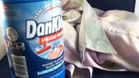 Eine Flasche DanKlorix steht neben einem schmutzigen Tuch, das in einem hellen Raum liegt, bereit für die Reinigung.
