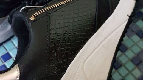 Weiße Sneakersohlen leicht reinigen mithilfe von Stahlfix und einer Zahnbürste. Schwarze Sneakers mit weißen Sohlen liegen auf einem gefliesten Boden, während sie zum Reinigen vorbereitet werden.