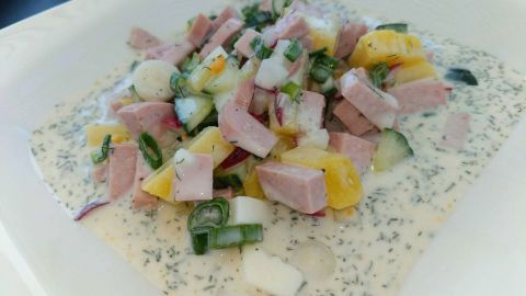 Eine bunte Mischung aus gewürfeltem Schinken, Gemüse und Kräutern schwimmt in einer kalten, sahnigen Suppe.
