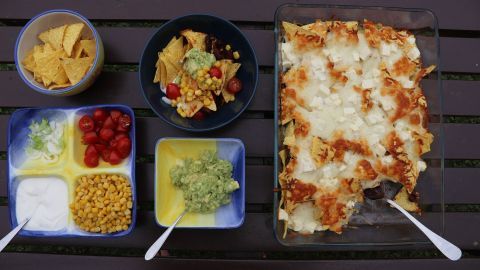 Überbackene Nachos liegen goldbraun und knusprig in einer Auflaufform, umgeben von frischen Zutaten und Dips.