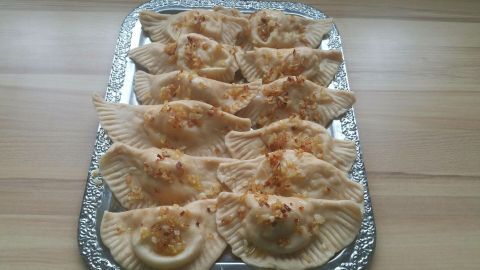 Piroggen mit Kartoffel-Zwiebel-Quark-Füllung liegen appetitlich auf einer silbernen Platte und warten auf den Verzehr.
