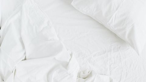 Ein ungemachtes Bett mit weißen Laken und einem Kopfkissen wirkt unordentlich und benötigt Pflege, um länger frisch zu bleiben.