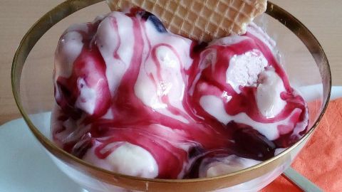 Cremiges Mascarpone-Amarena-Kirsch-Eis in einer Schale mit einer Waffel, serviert auf einem weißen Teller.