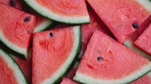 Stücke von Wassermelone liegen übereinander, mit saftigem, rotem Fruchtfleisch und grüner Schale sichtbar.