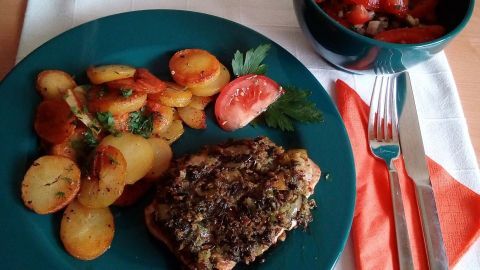 Saftige Schweinekoteletts mit einer Wasabi-Kruste liegen neben knusprigen Bratkartoffeln und einem bunten Salat in einer Schüssel.