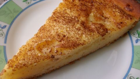 Ein Stück Griesskuchen liegt auf einem dekorativen Teller und zeigt die goldene, leicht gebräunte Oberfläche in einer heimeligen Umgebung.