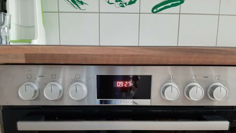 Ein Herd mit sechs hervorgehobenen Knöpfen zeigt die Zeit von 09:27 an, umgeben von einer modernen Küche.
