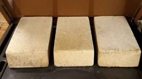 Drei dicke Speichermaterialien liegen auf einem Holzofen, während sie bereit sind, Wärme effizient zu speichern.