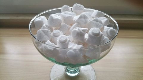 Eine Glas-Schale enthält viele weiße Spülmaschinentabs, die ordentlich gestapelt sind.