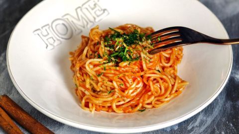 Ein Teller Spaghetti ist mit einer aromatischen Soße belegt, während eine Gabel sie aufnimmt, um sie zu genießen.