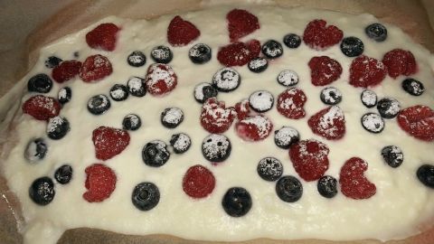 Süße, kalorienarme Snackfläche mit Joghurt, garniert mit frischen Himbeeren und Heidelbeeren auf Backpapier.