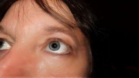 Ein Auge mit einer Wimper, während es aufmerksam nach oben schaut. Der dunkle Hintergrund betont den Fokus.