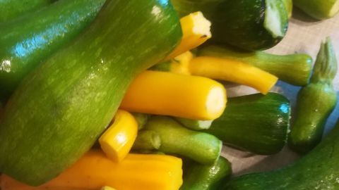 Leuchtende grüne und gelbe Zucchini liegen auf einem Tisch, bereit zur Zubereitung falscher Salzgurken aus Kürbis und Zucchini.