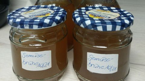 Gläser mit Gemüsebrühe stehen auf einem Tisch, beschriftet und gut verschlossen, bereit zur Resteverwertung.