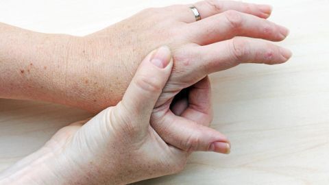 Hände liegen nebeneinander, eine greift die andere sanft, um eine Warze möglicherweise mit Schulkreide zu behandeln.