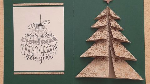 Eine gefaltete Weihnachtskarte zeigt einen dreidimensionalen Tannenbaum aus braunem Papier und einen Grußtext.