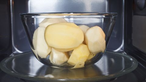 Kartoffeln werden in einer Glas-Schüssel ohne Wasser in der Mikrowelle gegart, um sie schnell zuzubereiten.