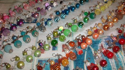 Bunte Schutzengelchen aus Perlen sind auf einem Tisch angeordnet und warten darauf, für DIY-Projekte verwendet zu werden.