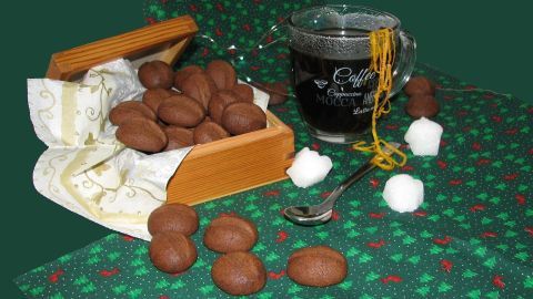 Kaffeebohnen liegen in einer box, während ein glas Cafe Brulot daneben steht, umgeben von dekorativem tischmaterial.