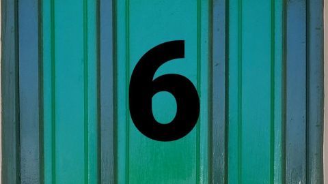 Ein grünes Türblatt zeigt die Zahl 6, bereit für eine Entdeckung hinter einem Adventskalender, in einem simplen Umfeld.
