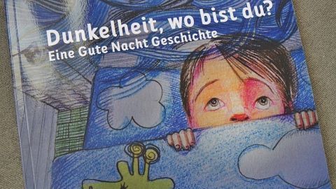Ein Kind schaut ängstlich unter der Decke hervor, während Wolken und ein kleiner Giraffenfreund bemalt sind.