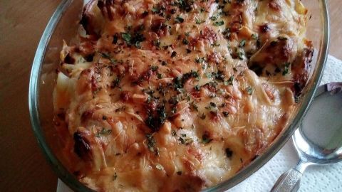 Ein goldbrauner Blumenkohl-Hackfleisch-Auflauf ist in einer Glasschüssel serviert und steht auf einer Holzoberfläche.