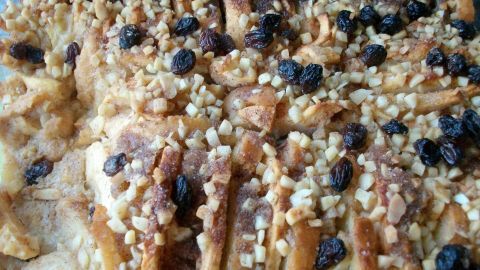 Ein süßer Apfelauflauf, frisch aus dem Ofen, mit knusprigen Brötchen, Äpfeln und Nüssen, verziert mit Rosinen.