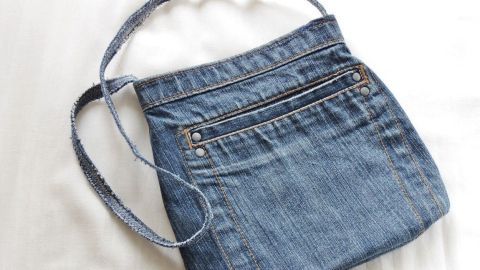 Eine Umhängetasche aus alter Jeans liegt auf einem hellen Untergrund, bereit für den Einsatz im Alltag.