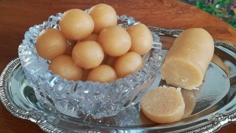 Runde, goldenbraune Marzipan-Kugeln liegen in einer kristallenen Schüssel auf einem silbernen Tablett, daneben ein Stück Marzipan.