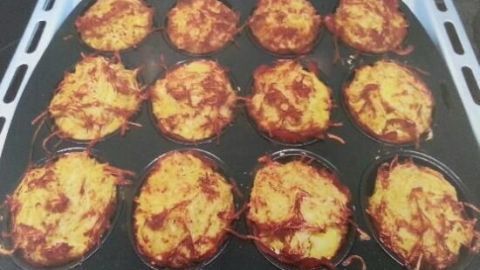 Rösti-Muffins befinden sich auf einem Blech und sind goldbraun gebacken, bereit zum Servieren in einer modernen Küche.