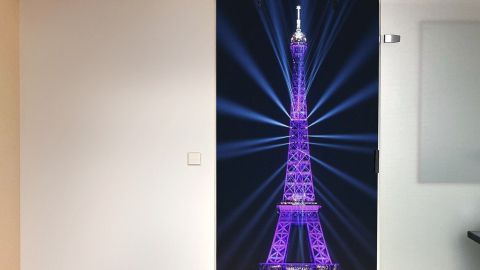 Eine Verdunkelungstür auf Rollen zeigt den leuchtend lila Eiffelturm, der in einem modernen Raum als Dekoration dient.