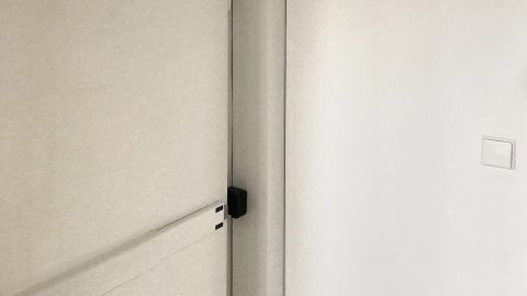 Eine helle Abdeckung für Heizungsrohre steht neben einer weißen Tür im Flur und schützt die Rohre im Wohnraum.