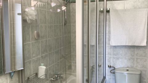 Eine Glasduschwand steht in einem modernen Badezimmer, während die Dusche bereit ist, genutzt zu werden.