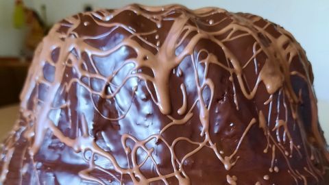 Ein saftiger Rotweinkuchen mit Dinkelvollkornmehl, überzogen von schokoladiger Glasur, steht auf einem Teller in einer Küche.