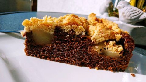Ein saftiges Stück russischer Birnenkuchen mit Kakaoboden liegt auf einem Teller und zeigt die fruchtige Füllung.