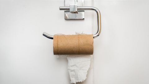 Ein Toilettenpapierhalter zeigt eine leere Rolle mit einem kleinen Stück weißem Papier in einem modernen Badezimmer.