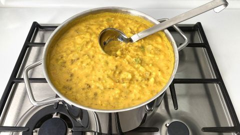 Ein schimmernder Topf mit Kürbis-Wirsing-Kartoffel-Eintopf steht auf dem Herd, bereit zum Servieren.