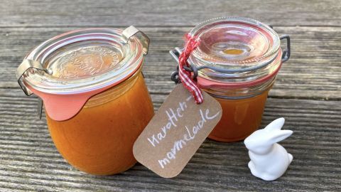 Zwei Gläser mit Karottenmarmelade stehen auf einem Holzuntergrund, neben einem kleinen weißen Hasen.