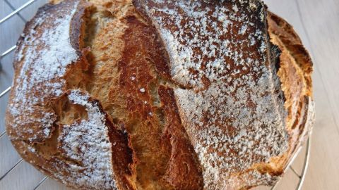 Ein frisch gebackenes Buttermilch-Dinkelbrot liegt auf einem Kuchengitter und zeigt eine goldbraune, knusprige Kruste.