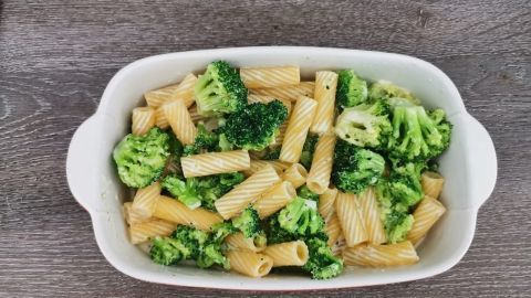 Tortiglioni und Brokkoli sind in einer weißen Schüssel angerichtet, umgeben von einem holzähnlichen Tisch.