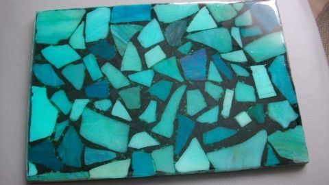 Ein gefliestes Epoxidharzstück zeigt eine Mosaikstruktur in verschiedenen Türkis- und Blautönen auf glattem Hintergrund.
